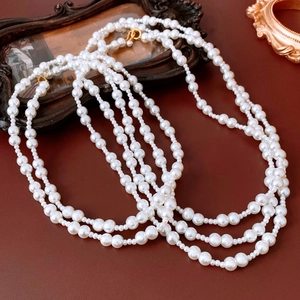 Detail of multi-layer white pearl necklace with gold clasp on vintage dark wood frame