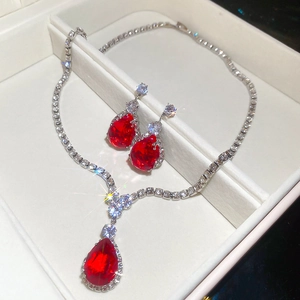Macro view of pear-shaped red gemstone necklace and earrings set in a white display box