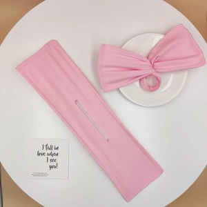 Detailed view of pink bow hair tie and matching bun maker set on a white table