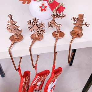 Close-up of four bronze metal Christmas stocking hooks with snowflake and reindeer motifs