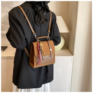 Mochila de cuero marrón vintage con dije de llave y cinta mostrada en un ambiente hogareño