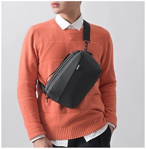 Close-up of black nylon crossbody bag with SPORT logo on male model in orange sweater