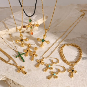 Gold stainless steel cross necklace set with green and brown gemstones on stone background