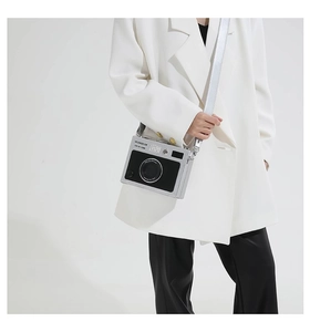 Detail view of a vintage camera-shaped crossbody bag with silver strap on model