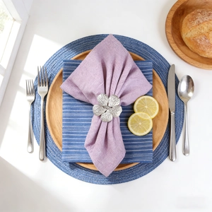 Flat lay of silver plum flower napkin ring on purple linen napkin and wooden plate