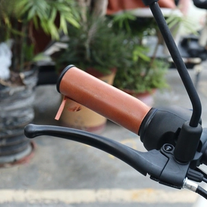 Close-up of vintage brown leather handlebar grip with tassel on black motorcycle handle