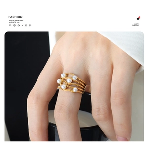 Detail of vintage wavy gold ring with pearls worn on hand holding a black mug