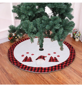 Detail of white Christmas tree skirt with red buffalo plaid trim and Santa Claus appliques