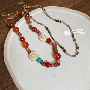 Detail view of retro beaded necklaces with agate and shell on a ceramic plate