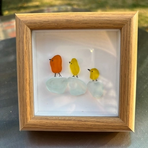 Vue macro d'oiseaux en verre de mer avec des poussins orange et jaunes sur cadre en bois