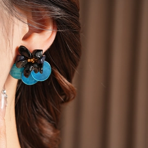 Close-up of vintage floral earrings with blue sequins worn by a model in soft light