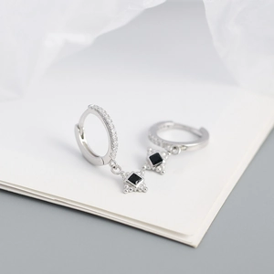 Detail of s925 silver hoop earrings featuring square black pendants and crystal accents