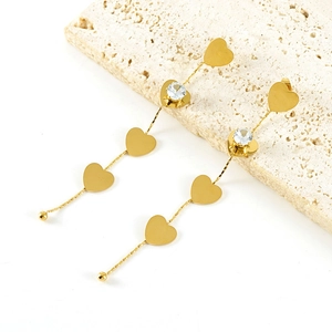Detailed shot of long gold tassel earrings with heart motifs and clear zircons