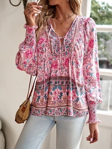 Close-up of bohemian floral print on pink long sleeve V-neck blouse with tie details