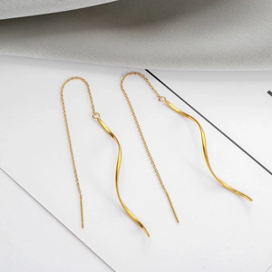 Gros plan de boucles d'oreilles vagues dorées avec finition polie sur fond de soie blanche