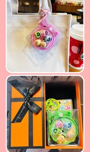 Close-up of camera-shaped keychain with colorful pet toys inside on a canvas bag