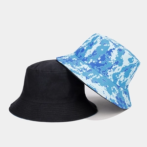 Detail view of double-sided bucket hats in plain black and blue pixel camouflage pattern
