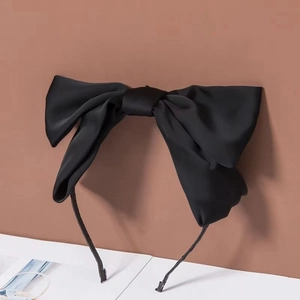 Detail showing the large black satin bow hair clip with smooth fabric texture and elegant finish