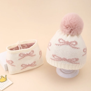 Detail of baby winter knit hat with pink bow pattern and fluffy pompom ornament