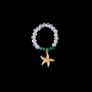 Detailed close-up of elastic bead ring featuring a golden starfish pendant and green beads