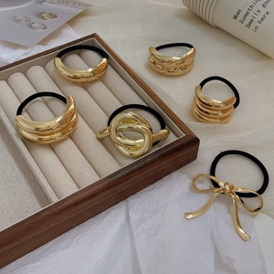 Detailed view of assorted gold metallic hair ties with various textures on a velvet display