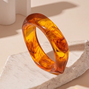 Detail view of translucent amber acrylic bangle with dark marble texture on mineral stone