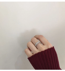 Close-up of a double-layered zircon petal ring styled with a dark red sweater
