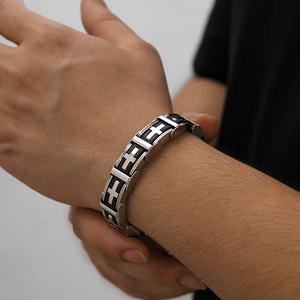 Close-up of a men's stainless steel cross bracelet with black silicone and silver links