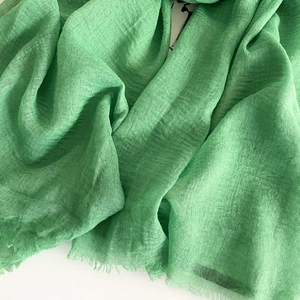 Close-up of grass green cotton linen scarf showing breathable fabric and raw fringe edges