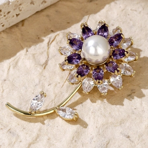 Detailed view of a gold flower brooch featuring purple crystals and a white center pearl