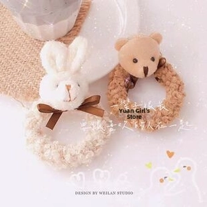 Detail of plush bear and rabbit hair ties with elegant satin bows in a cozy setting
