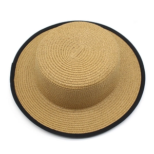 Detailed close-up of a flat top straw hat with a contrasting black ribbon edge detail