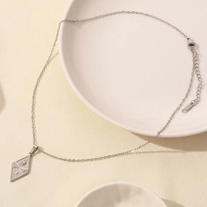 Detailed close-up of a silver stainless steel diamond-shaped pendant with celestial symbols