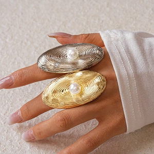 Detailed view of large pearl rings with wavy textured metal in gold and silver finish