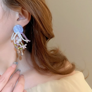 Détails de boucles d'oreilles en perles faites main avec pompons bleus sur un modèle