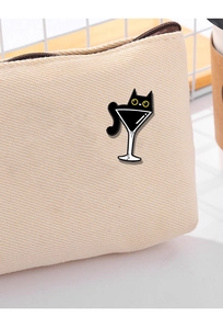 Detailed close-up of a black cat enamel pin attached to a beige canvas tote bag