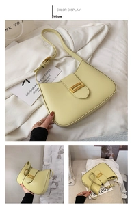Detail of light yellow leather baguette bag featuring a rectangular gold metal buckle