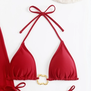 Detail of red halter bikini top featuring a golden heart-shaped metal buckle connector