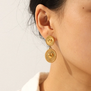 Close-up of a model wearing 18K gold heart-shaped geometric stainless steel drop earrings