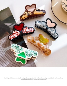 Flat lay of five acetate heart-shaped hair claws in various patterns on a magazine