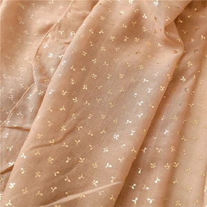 Close-up of beige mesh scarf featuring gold sequin patterns and delicate rolled edges
