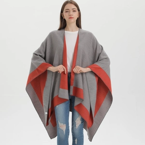 Detail of grey knit poncho cape with contrast orange-red stripes and split hem design