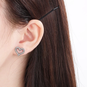 Close-up of sparkling silver heart stud earrings with pave crystals worn by a model