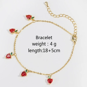 Detailed view of strawberry gold bracelet with red heart crystals and green leaf charms