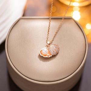 Rose gold shell necklace with pearl and rhinestones displayed on a jewelry stand