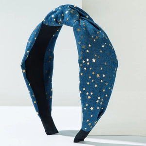 Blue denim knotted headband with gold stars on a white geometric display block