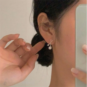 Minimalist 925 sterling silver pearl earrings with crossover design on a model