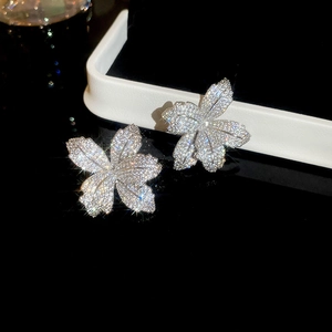 Macro shot of silver flower stud earrings with shimmering zircons on a black display stand