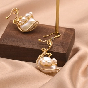 Elegant swan-shaped gold wire earrings with baroque pearls and small crystals on satin