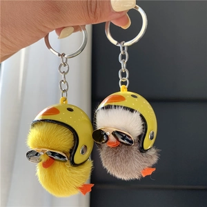 Close-up of plush duck keychains with yellow helmet and sunglasses on mink fur